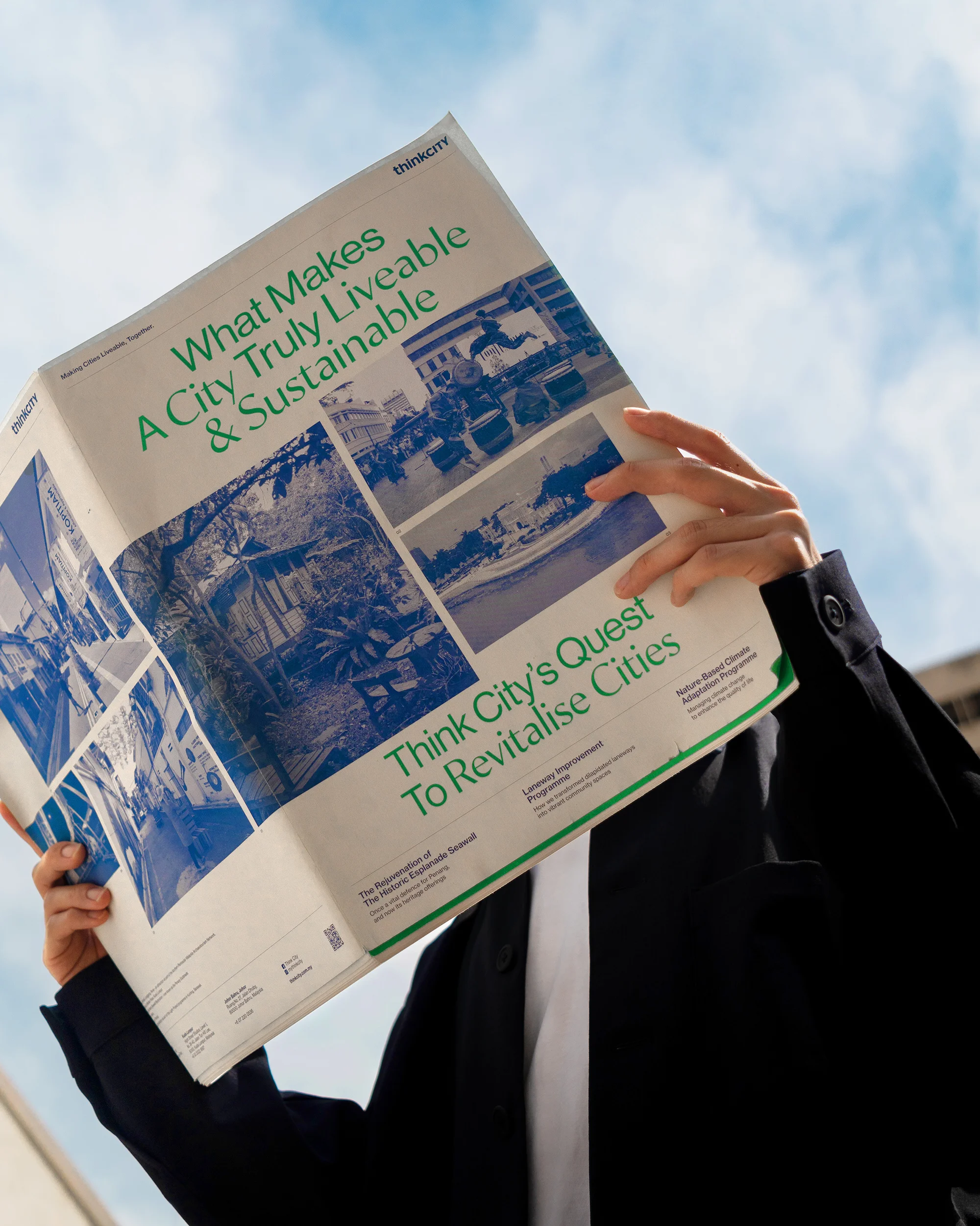 Person in a suit reading a Think City report titled 'What Makes A City Truly Liveable & Sustainable' with a blue sky background.