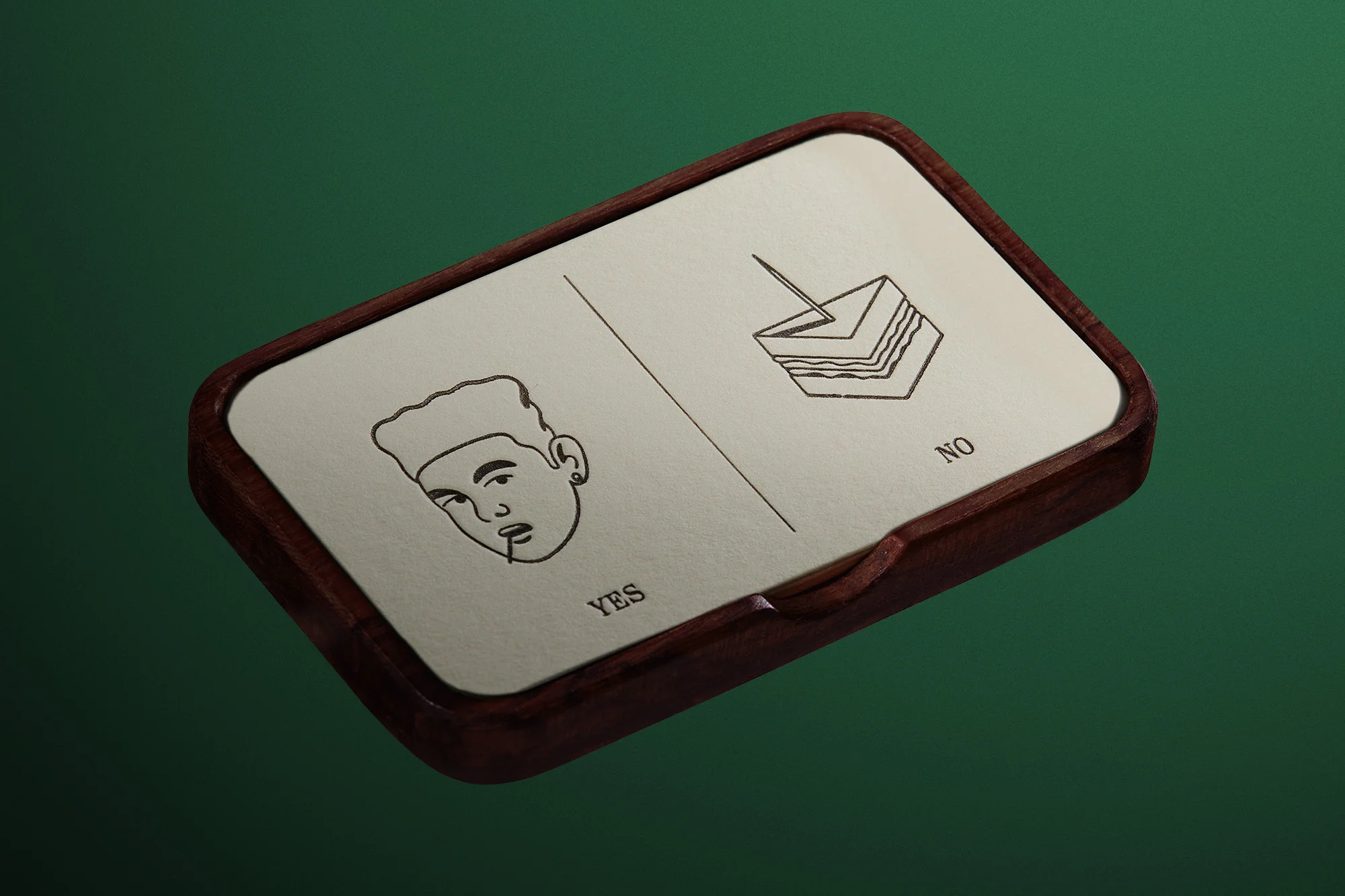 A close-up of a wooden box with line drawings of a person and sandwich with 'yes' and 'no' labels on a green background.
