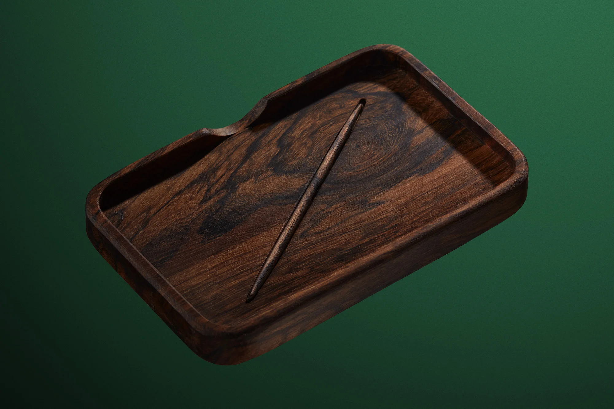 Dark wood tray with a dark wooden crochet hook on a green background, suitable for a craft or product shot. 