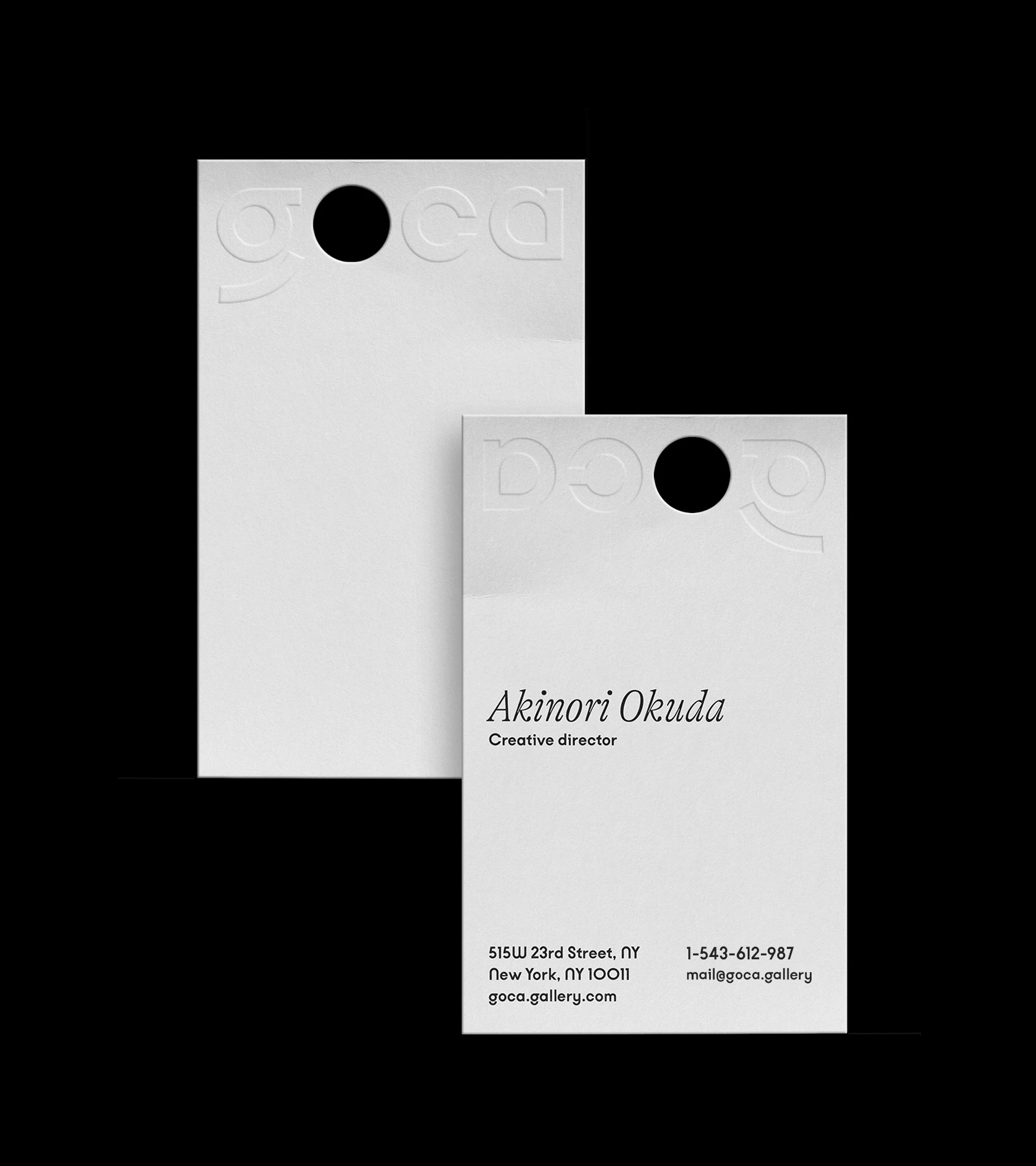 Two white cards with a die-cut hole at the top. Text reads: Akinori Okuda, creative director, address, phone number, and email.
