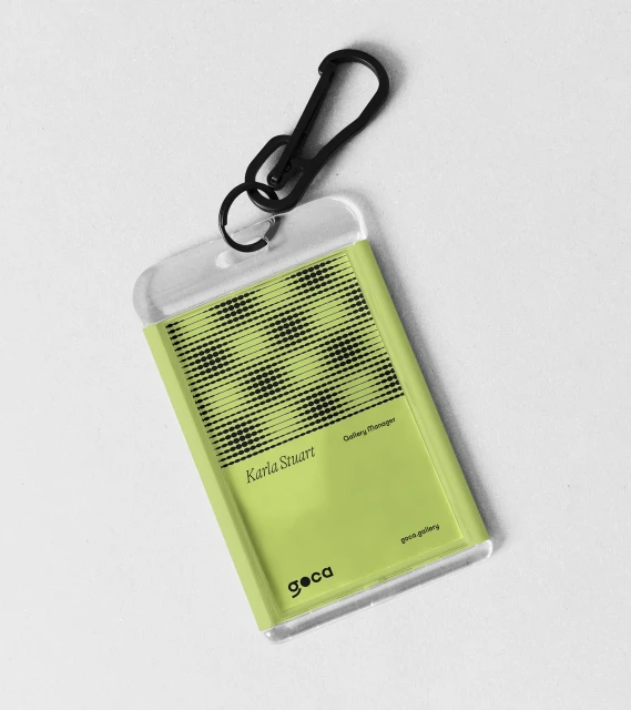 A light green plastic identification card with a black clip and a geometric pattern on a white background, photographed in studio lighting.