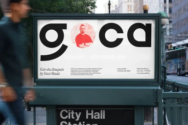 GOCA brand identity billboard displayed at a city transit station with bold typography and a portrait of a man