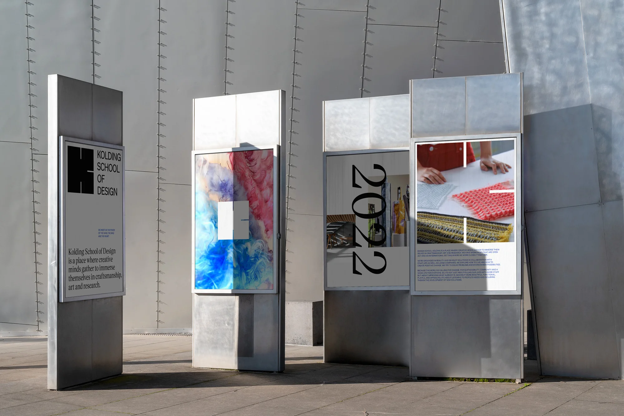 Outdoor metal information displays featuring design school posters with geometric patterns, typography, and student work showcase.