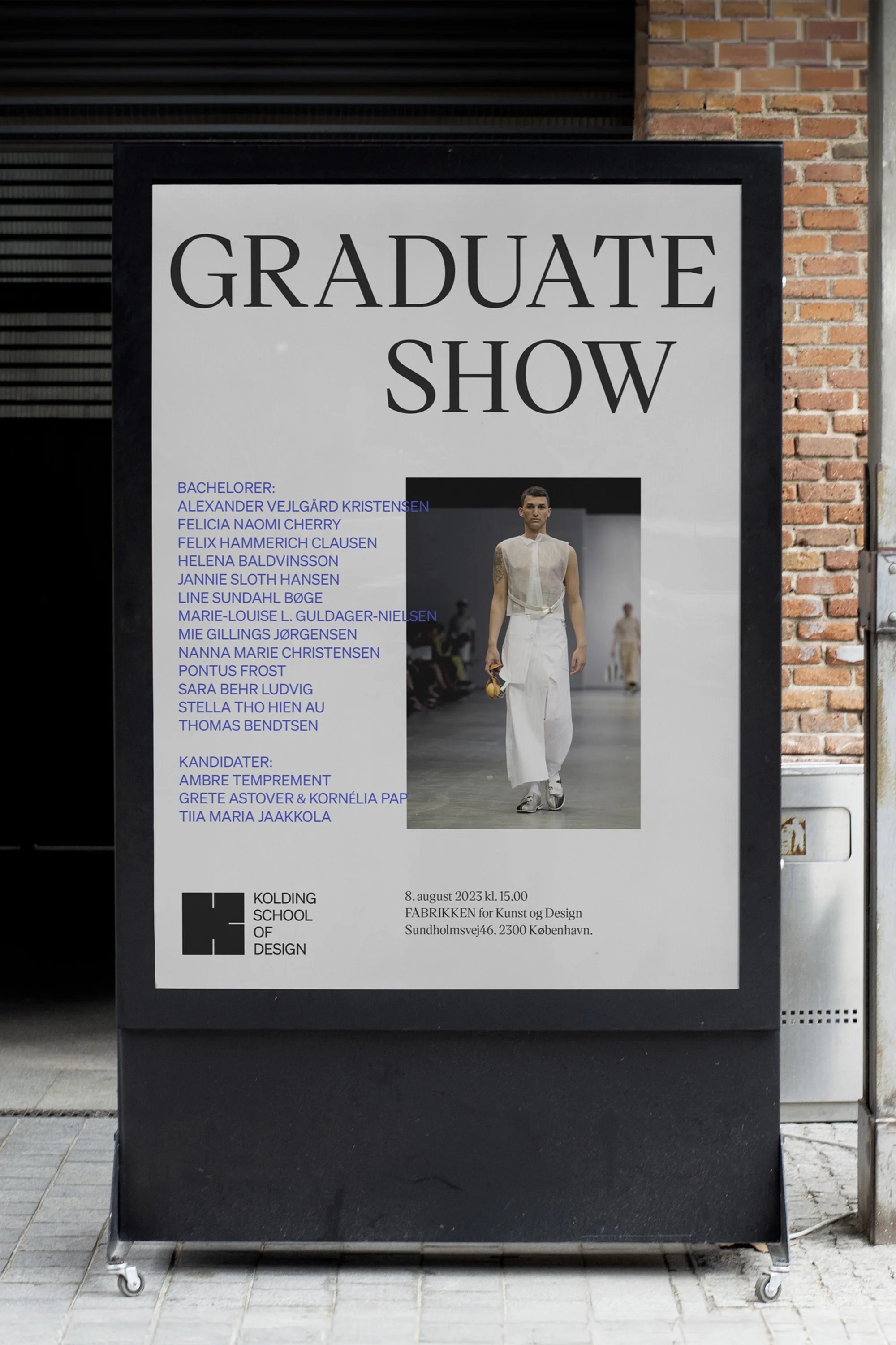 Poster for a graduate show displaying students names and a runway image, set against a brick wall and metal siding outdoors.