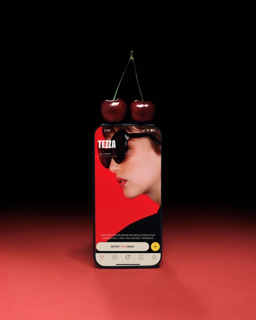 Smartphone screen displaying a woman wearing sunglasses and two cherries balancing on top, against a contrasting red and black backdrop.