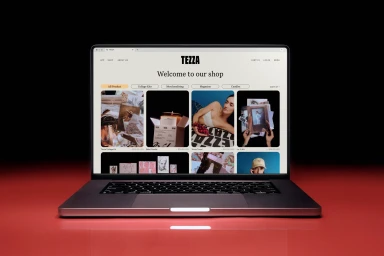 Laptop displaying the Tezza online shop interface on a glossy red reflective surface against a dark background.