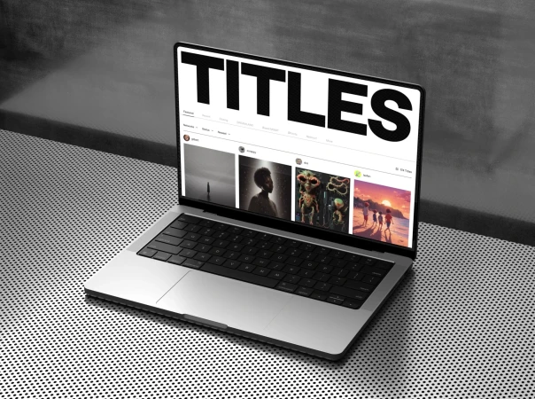 Silver laptop displays website titles on a black dotted table against a grey wall, showcasing digital design and modern technology.