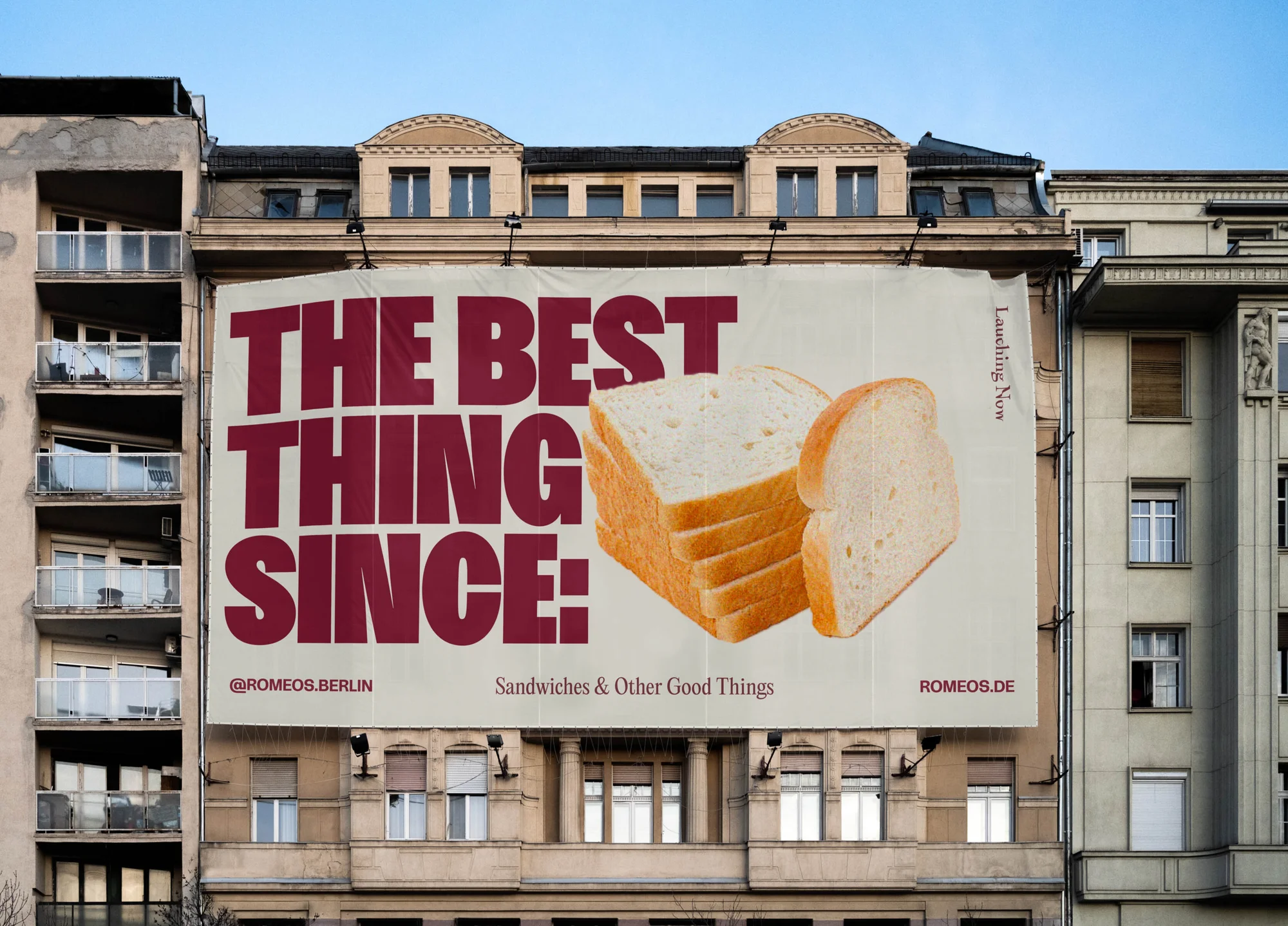 Building-mounted billboard ad for Romeos.Berlin featuring sliced bread with the tagline 'The Best Thing Since'.
