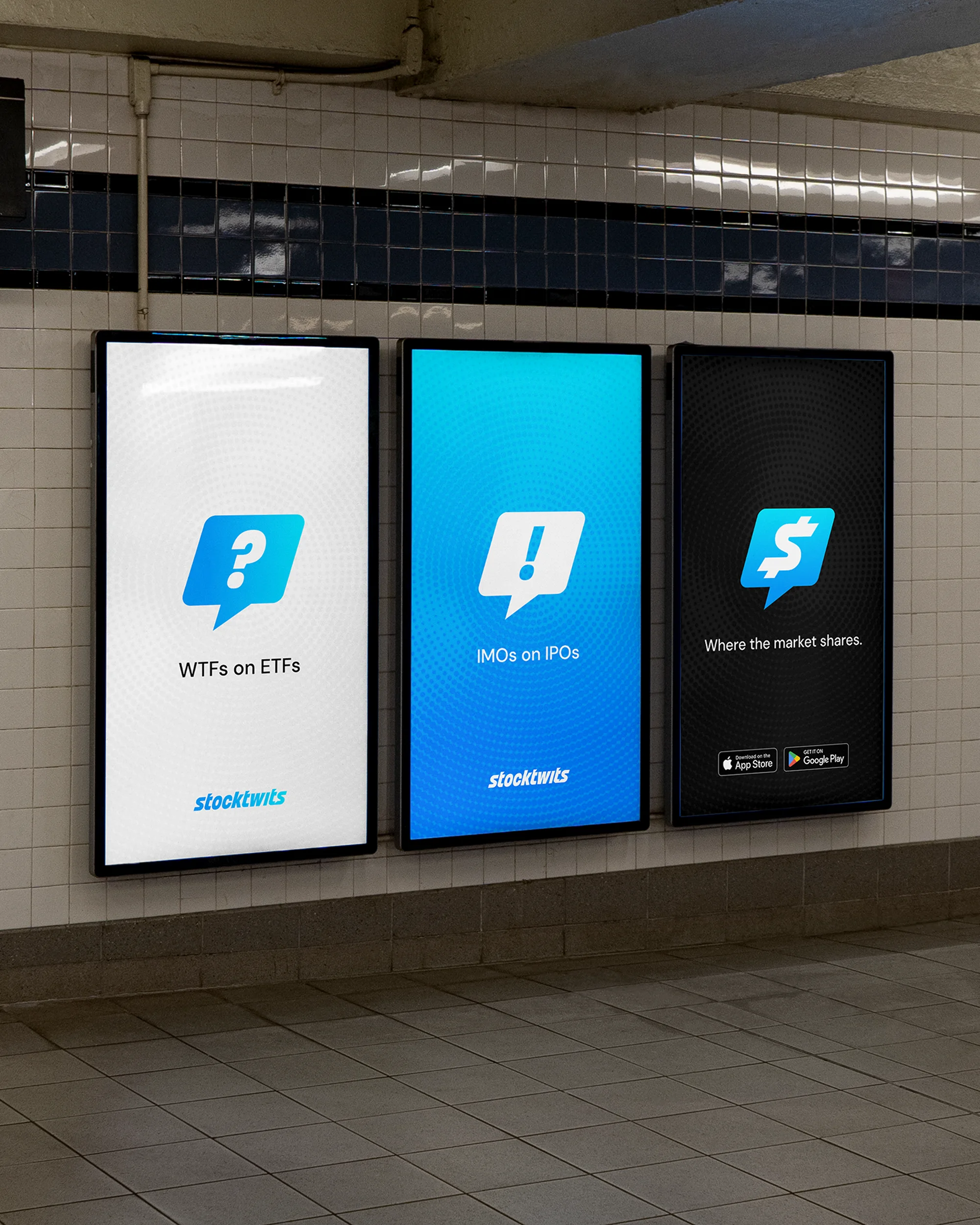 Stocktwits advertisements on three digital billboards in a subway station. Each features a blue speech bubble logo against white, blue, and black backgrounds.