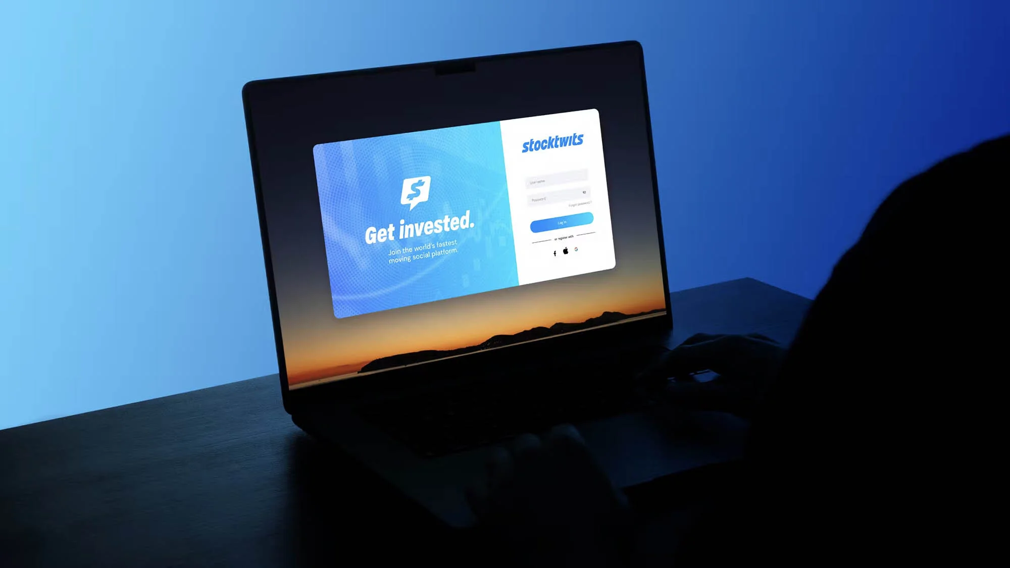 Laptop screen displaying the Stocktwits website, showcasing their slogan 'Get invested' against a gradient blue background.