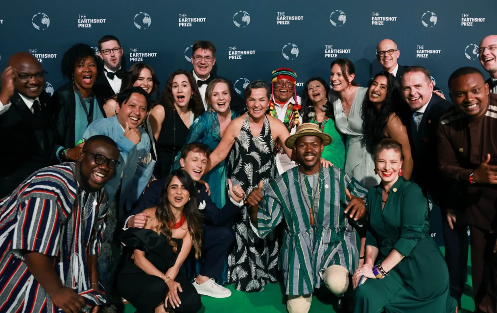 Wide shot of Prince William onstage at The Earthshot Prize ceremony, standing at a podium with a microphone and a screen behind him.