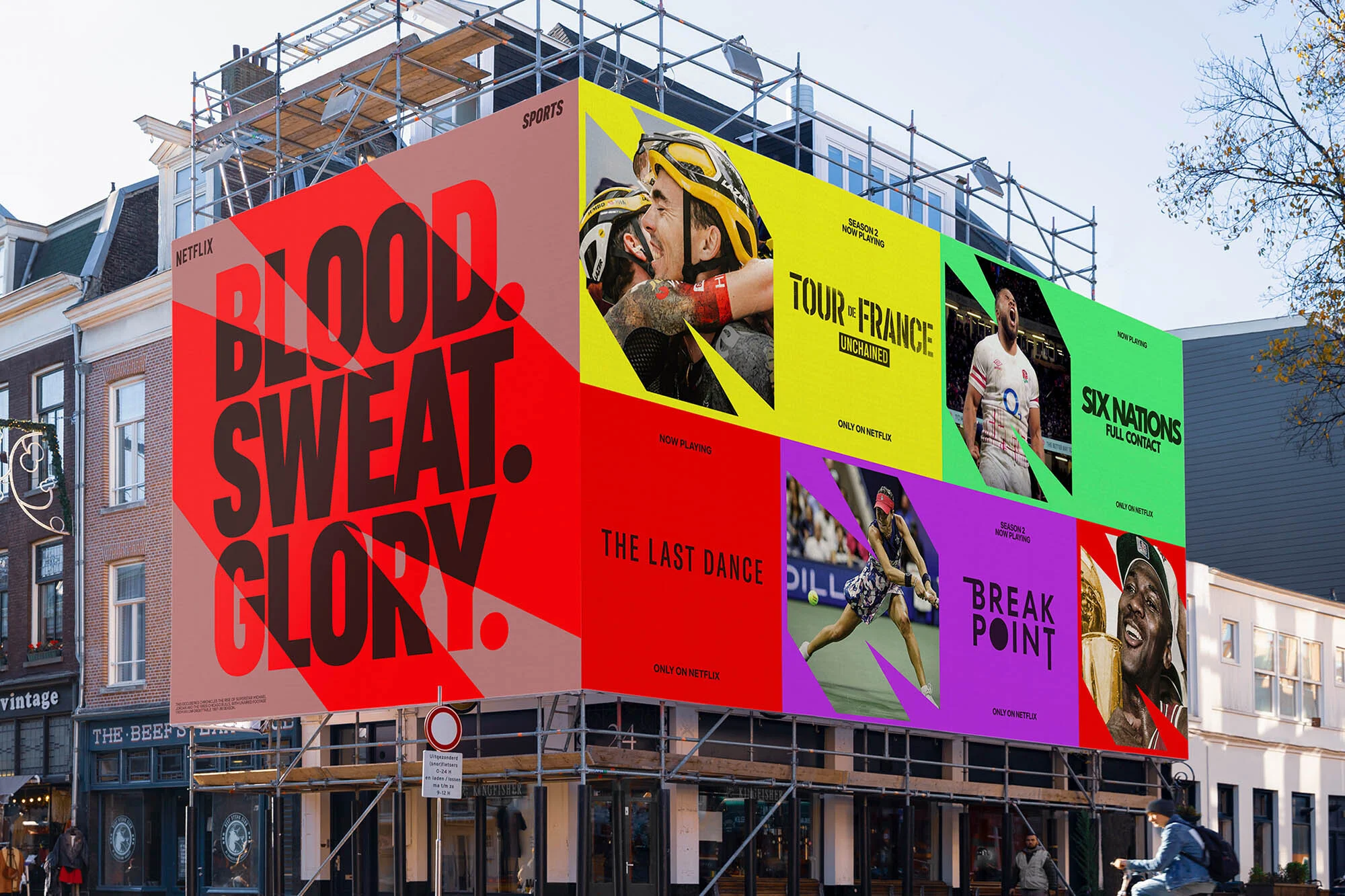 Large billboard on a city building promoting Netflix sports documentaries, including cycling, basketball, tennis, and rugby.