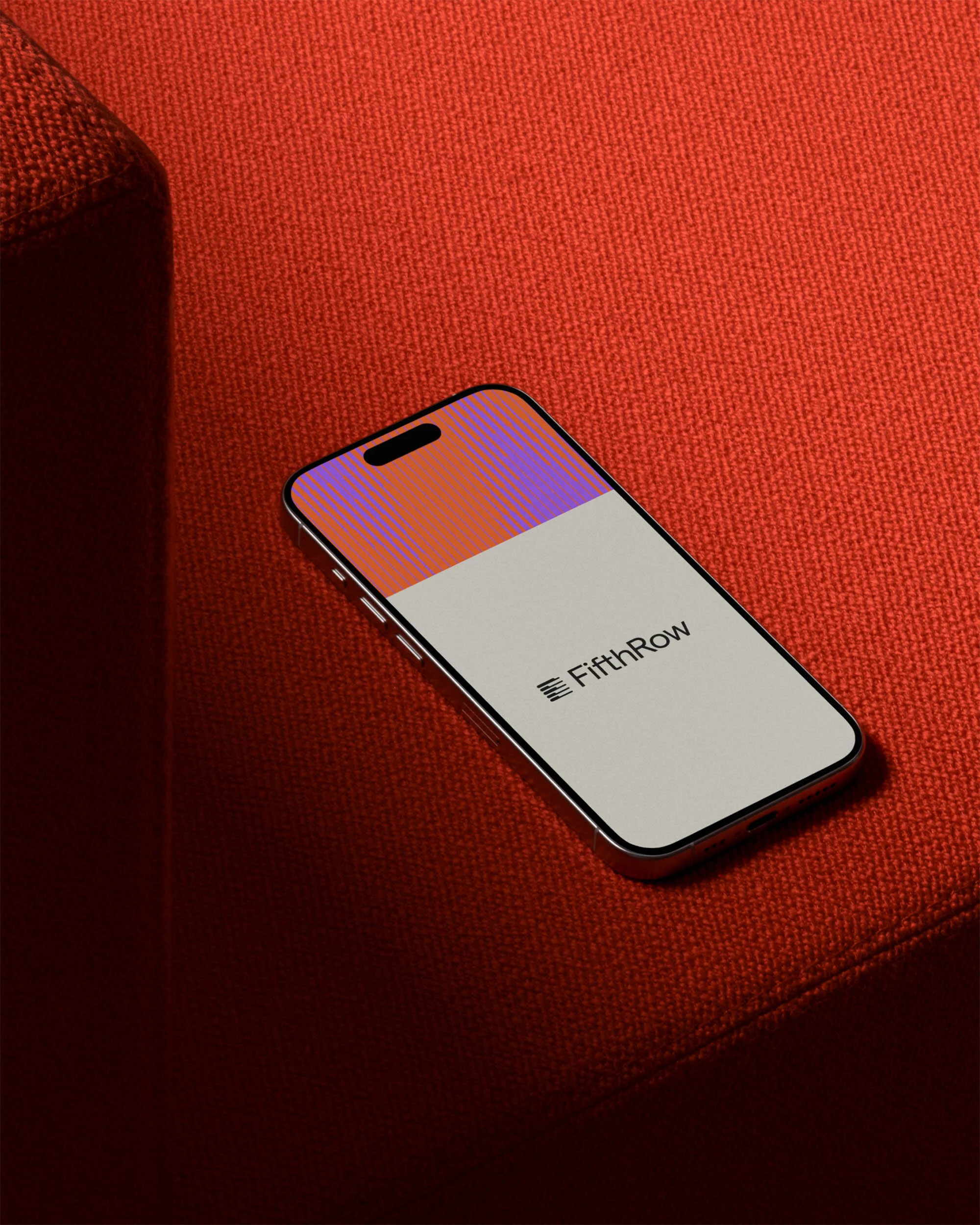 Smartphone displaying FifthRow on a red textured surface. The screen shows a split of orange/purple and white colors on the device.