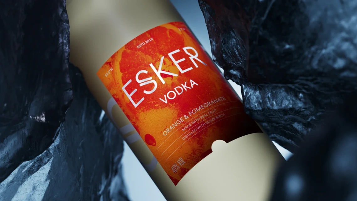 Esker Vodka bottle close-up. The label features vibrant orange and pomegranate colors, highlighting natural fruit ingredients.