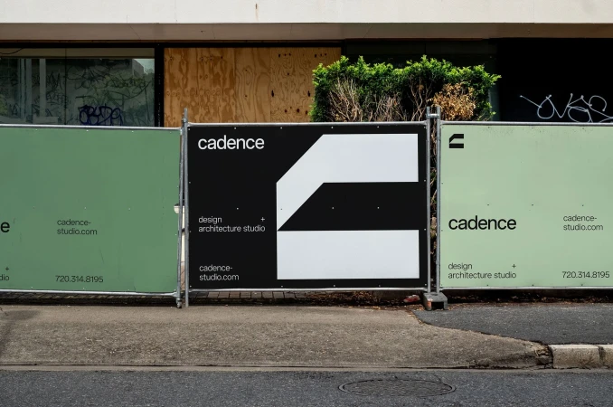 View of outdoor signage with the word cadence and a geometric logo in black and white, in front of a building with covered windows.