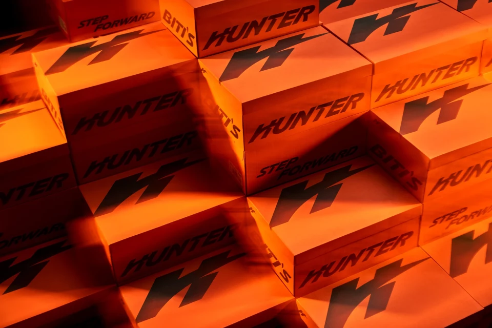 Close-up product shot of orange boxes with black graphics and brand text forming a staggered pattern. Ideal for marketing or advertising.