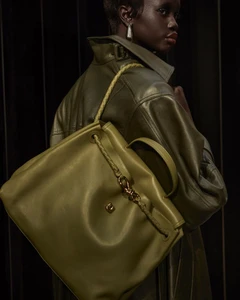 Model Aker Ajak wearing an olive leather jacket and holding an olive handbag in an editorial for Vogue Mexico