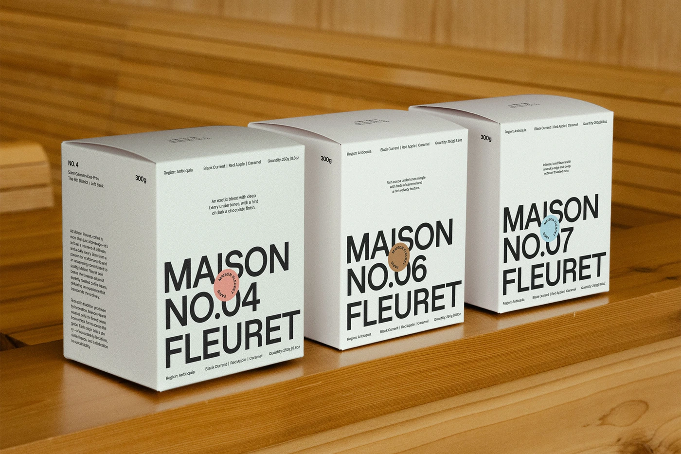 Three white coffee boxes with bold black typography arranged on a wooden slatted surface