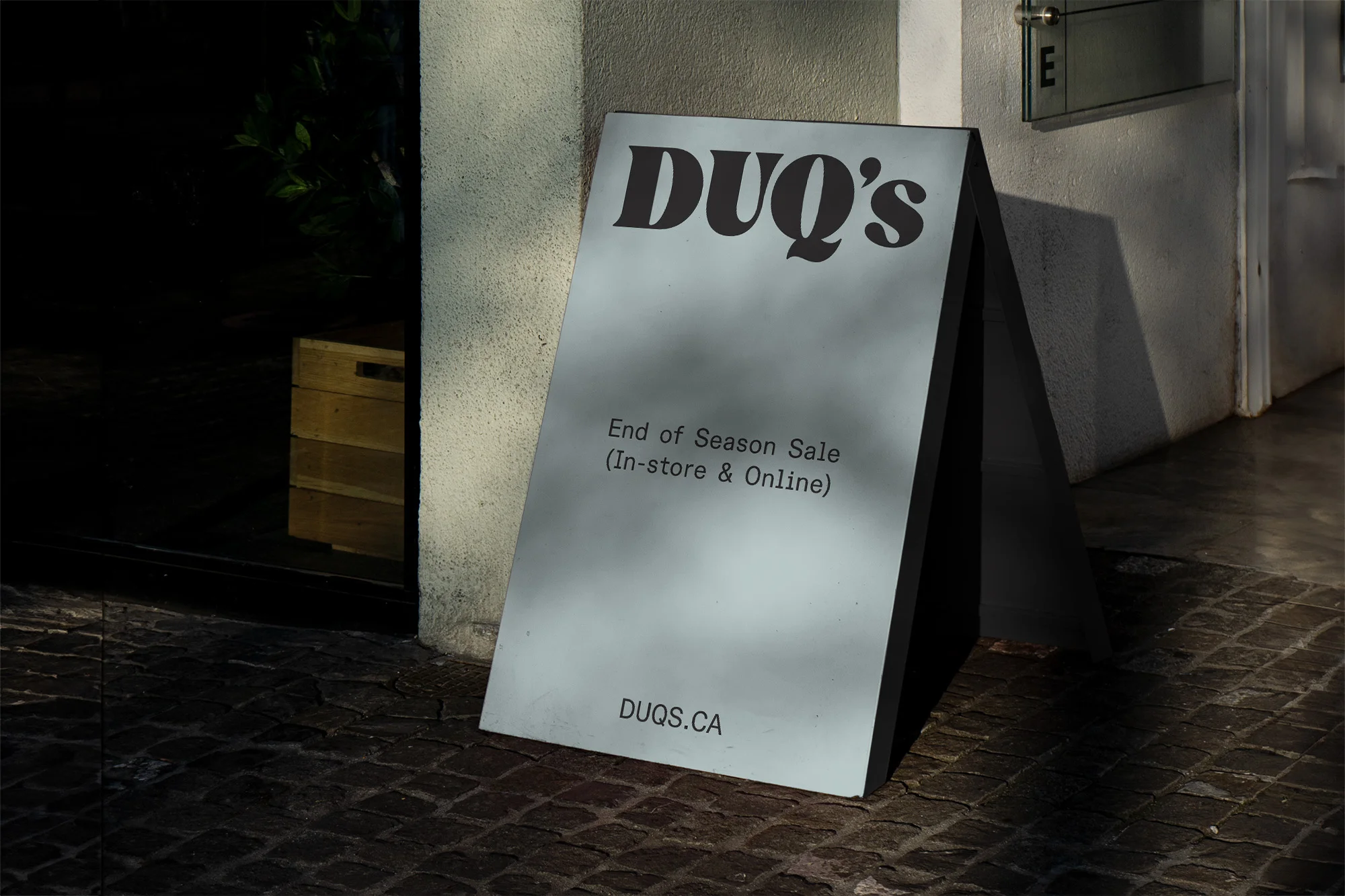 A-frame sign outside a store advertises an end-of-season sale, with the store name 'DUQ's' prominently displayed, creating an eye-catching promotion.