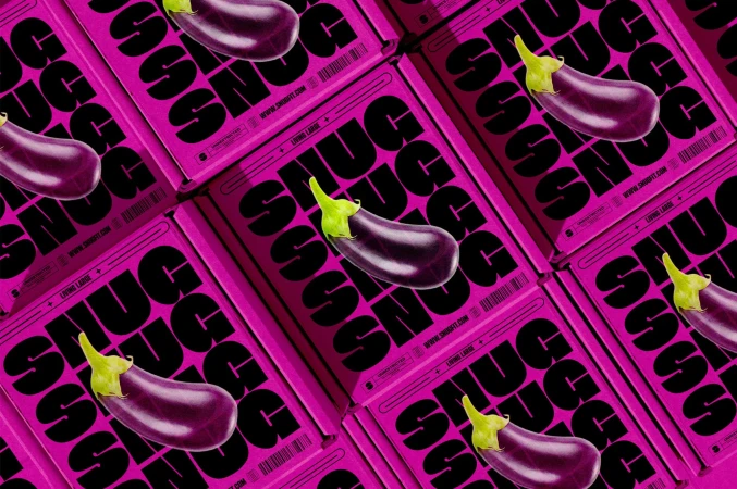 Overhead view of pink shipping boxes with the word 'SNUG' in bold black letters, each topped with a fresh eggplant.