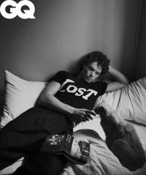 Sam Corlett lying on a bed with a cat and a book for GQ Australia