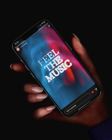 Hand holding a smartphone displaying 'Feel the Music' on a vibrant background with Instagram interface details, set against black.
