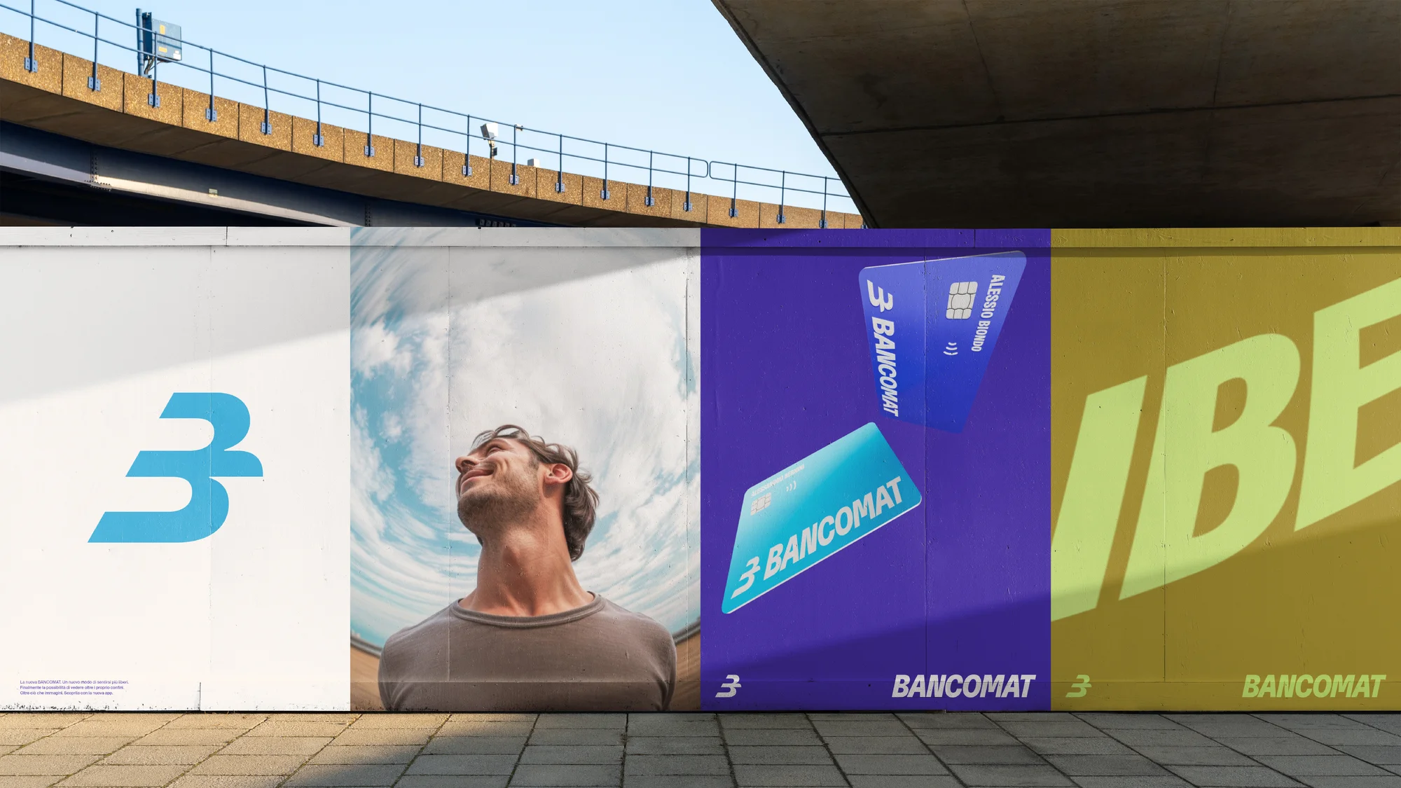 Outdoor advertising featuring a man looking up against a sky background, alongside bank card imagery and blue and yellow logos.