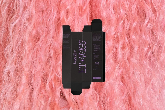 ET Wigs lace glue packaging on a backdrop of pink wavy hair. The box is black with pink text, displayed against a vibrant pink background.