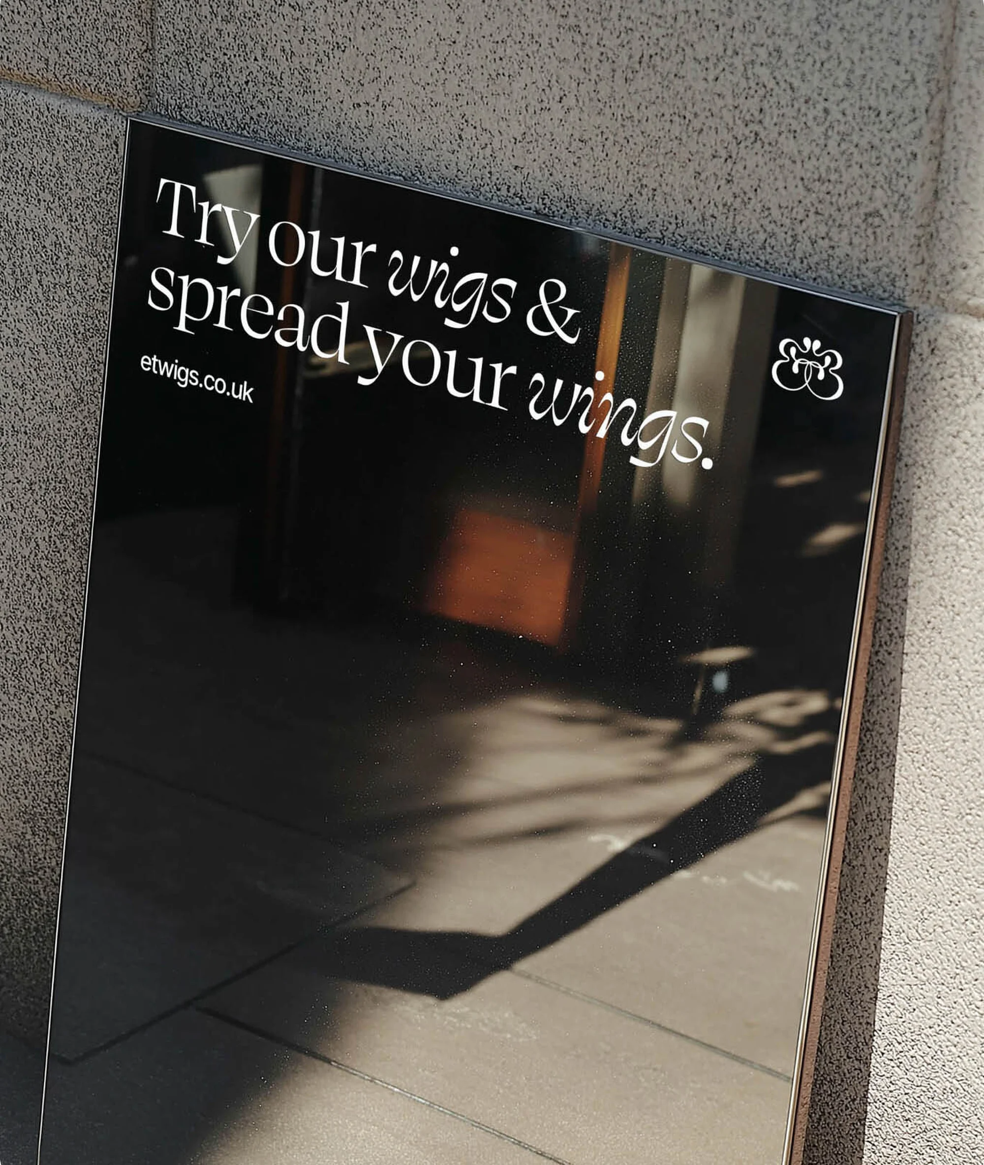 Advertisement featuring a dark background with the text 'Try our wigs & spread your wings' and an image reflecting the outdoors.