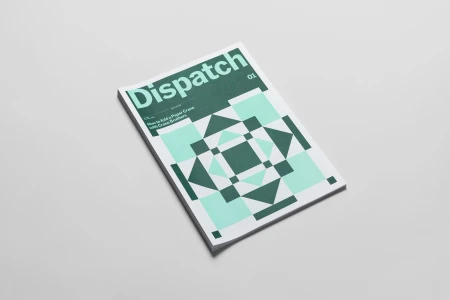 Printed magazine titled Dispatch resting on a plain white background with geometric green pattern cover.