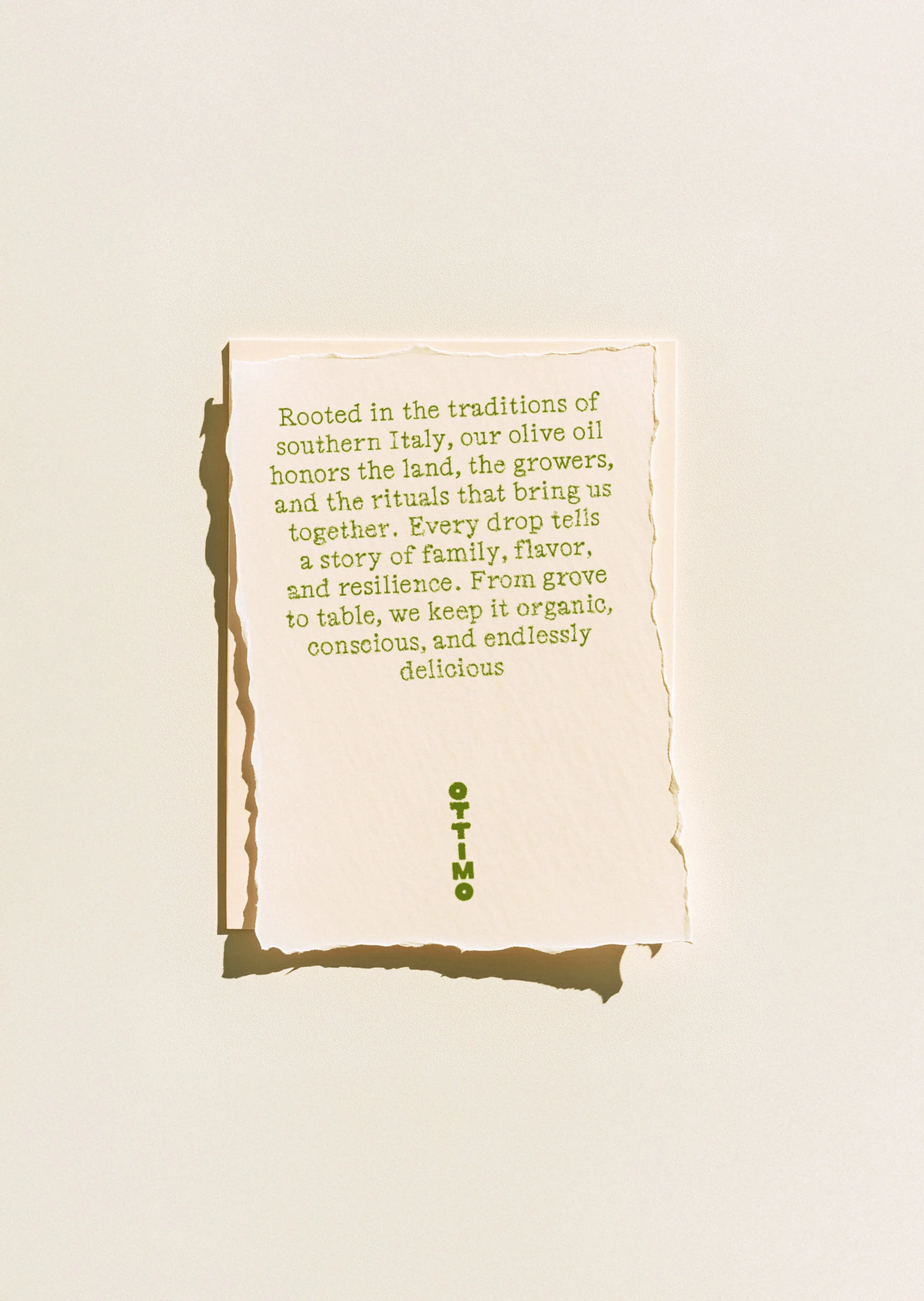 Close-up of a textured card featuring green text about olive oil rooted in Italian traditions, set against a light beige background.