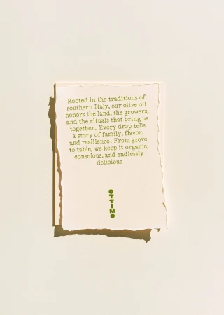 Close-up of a textured card featuring green text about olive oil rooted in Italian traditions, set against a light beige background.