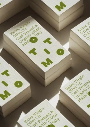 Stacked white textured product boxes with green OTTIMO branding and olive oil labels under natural light