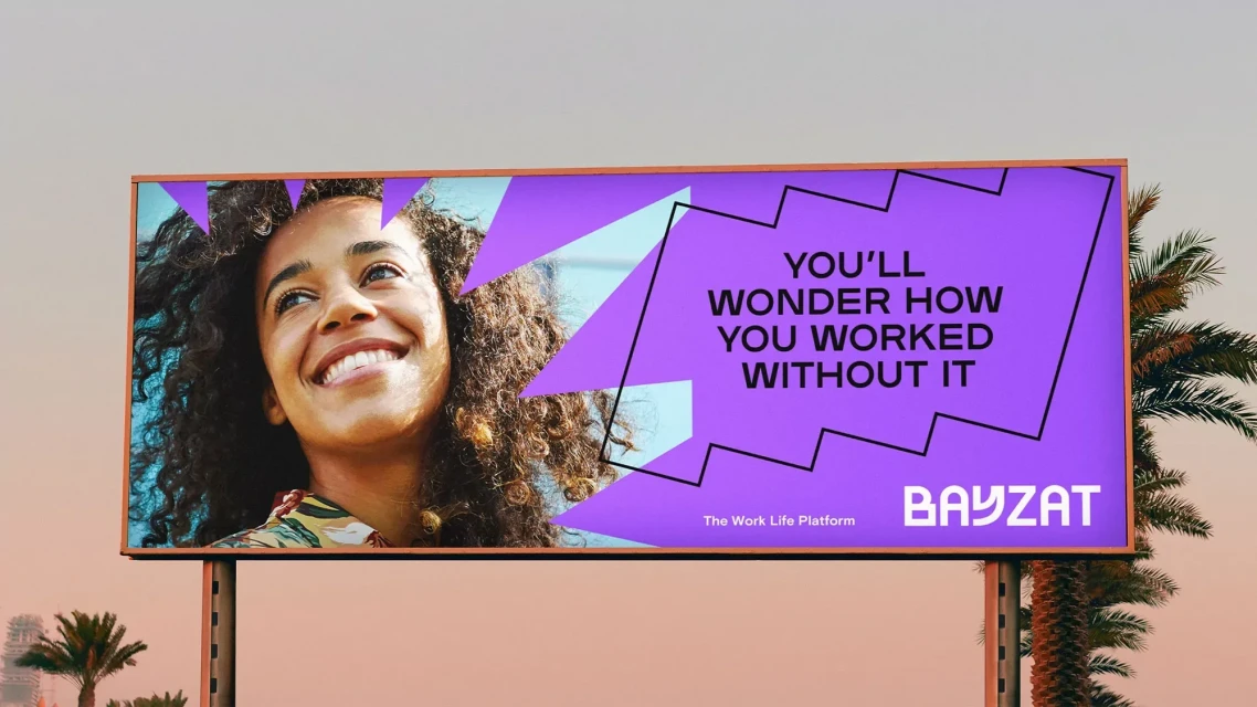 Outdoor advertising billboard with smiling woman and tech company logo against clear sky and palm trees in the background.
