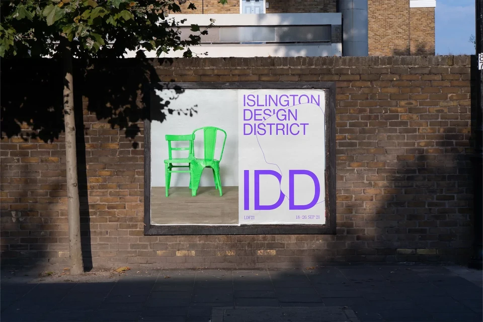 Outdoor advertisement for the Islington Design District featuring two green chairs, with a building and tree in the background.