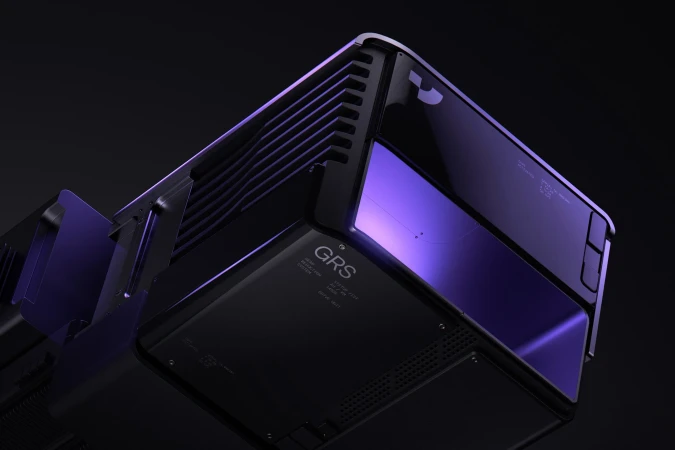 Close-up of a futuristic-looking black and purple electronic device with vents and subtle lighting, set against a dark background.
