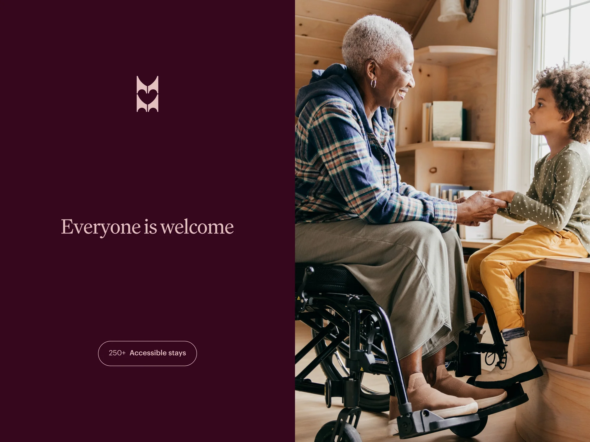 An elderly woman in a wheelchair is holding the hands of a child in a light-filled room with wooden walls and a shelf.