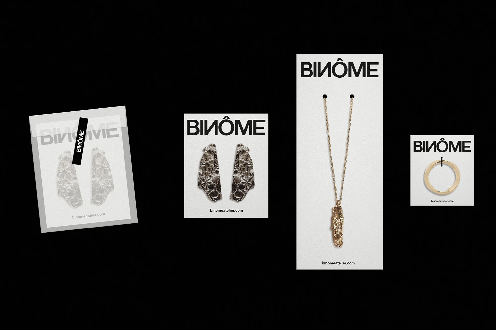 A flat lay features Binôme jewelry on cards against a black backdrop, showcasing earrings, a pendant necklace, and a ring for fashion.