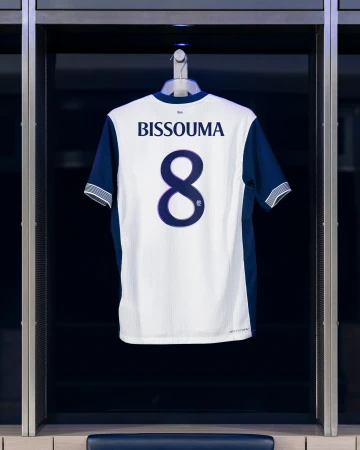 Tottenham Hotspur jersey with BISSOUMA and the number 8 on display in a locker room, representing the sport and club affiliation.