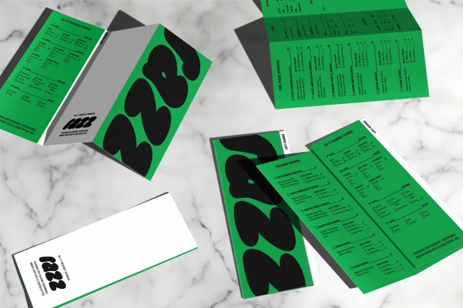 Overhead shot of a table featuring several folded bright green and black menus for the restaurant 'Jazz', arranged on a marble surface.