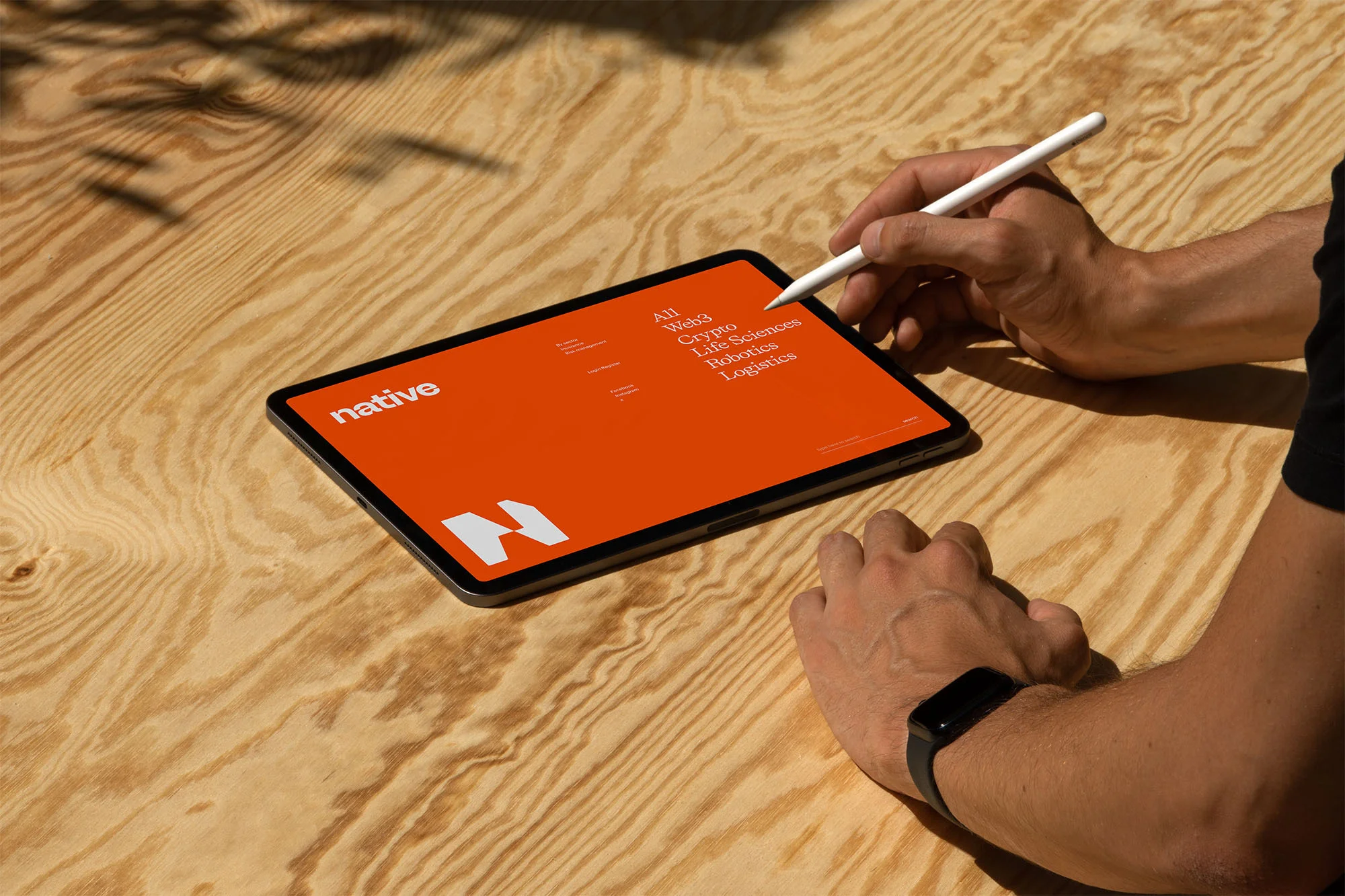 Person interacting with a tablet showing the brand name 'Native' and associated text on a light-colored wooden surface.