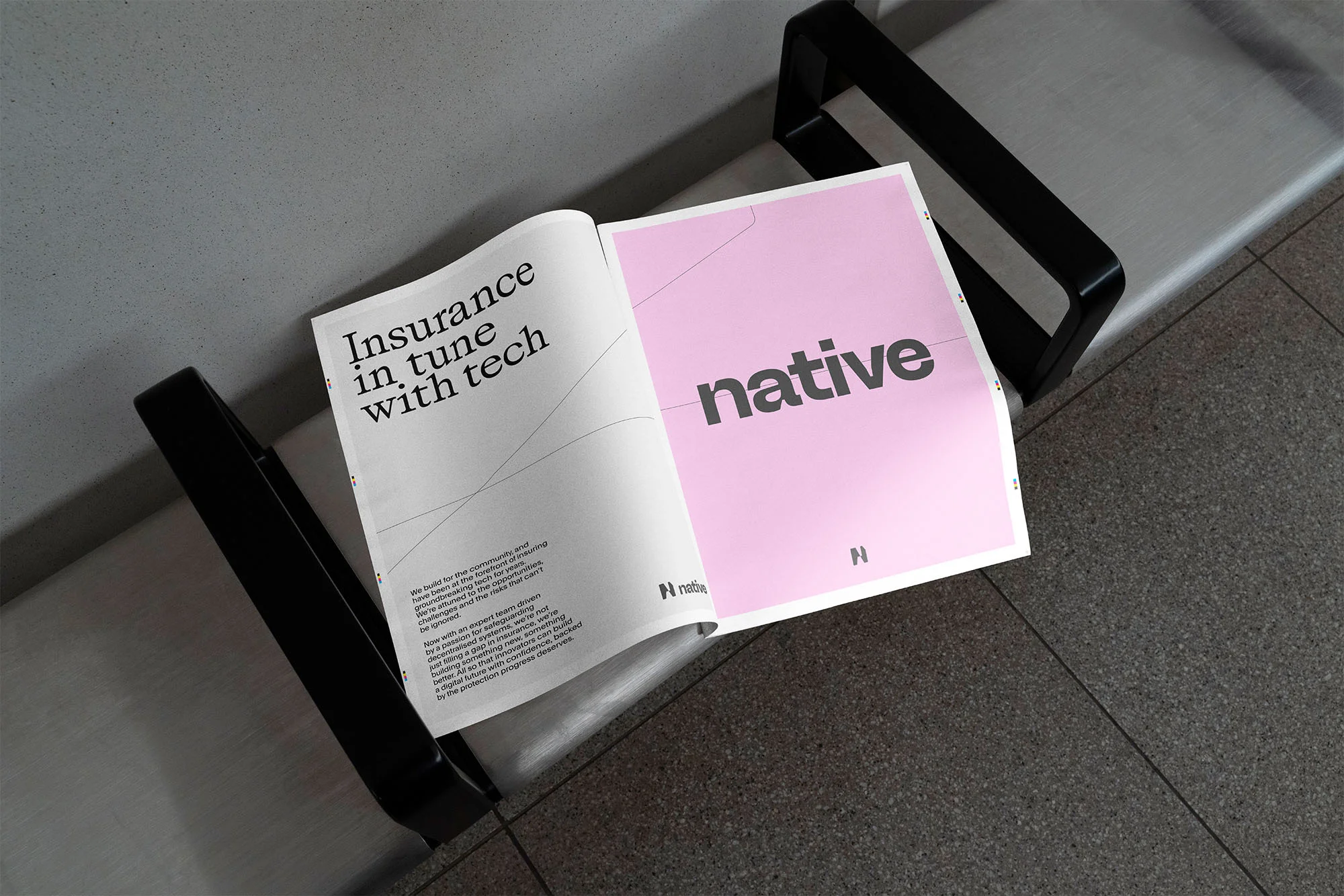 Open magazine with a pink page and the word 'native' in gray letters resting on a metal bench seat indoors.