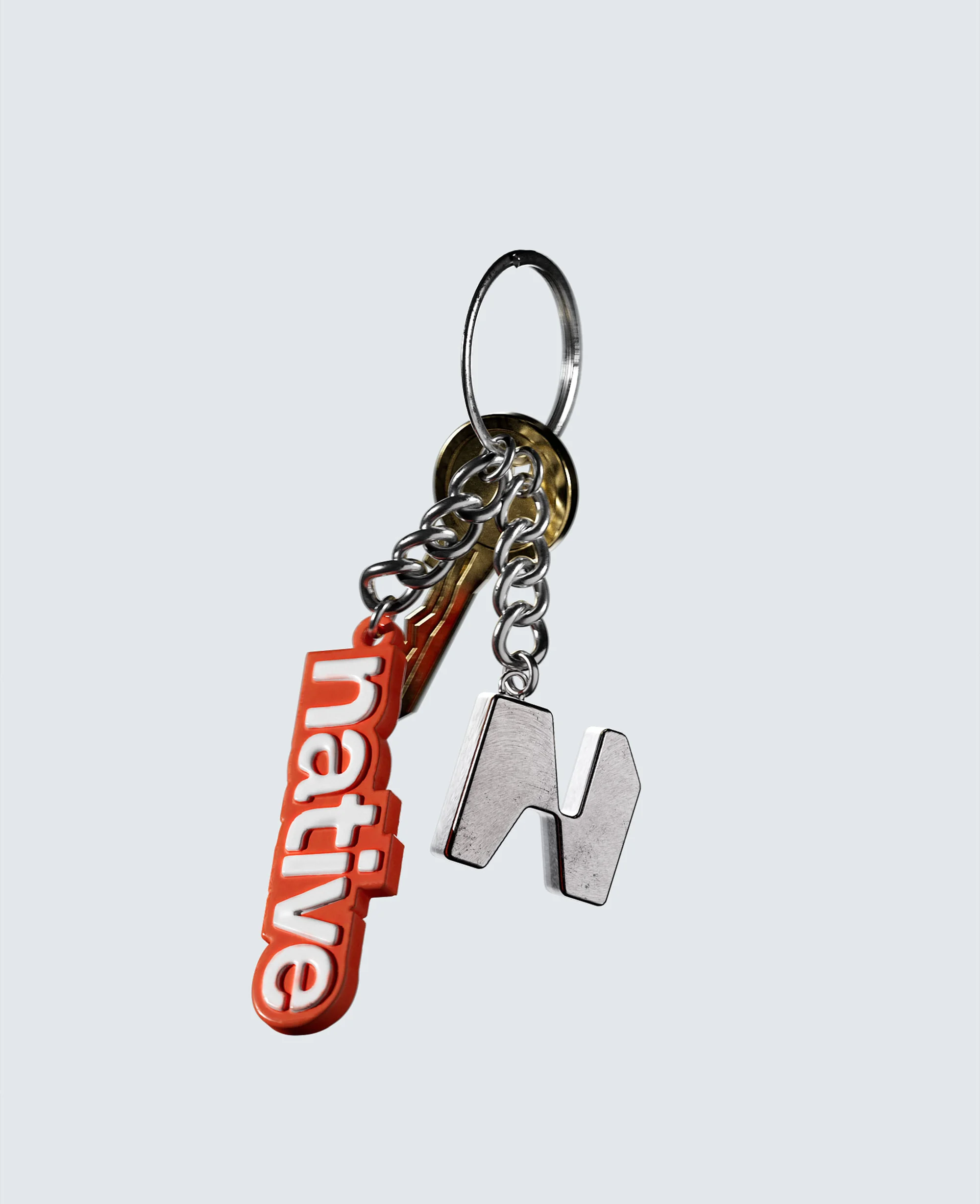 Close-up of a keychain with two charms, one orange with the word 'native' and a metal 'N' attached with silver chain and key ring.