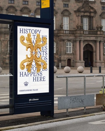 Outdoor advertisement in an urban setting showcases ornate gold flourishes and blue text for Christiansborg Palace on a bus stop.