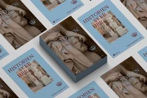 Multiple brochures featuring classical sculpture photography and Danish text laid out flat on a grey surface.