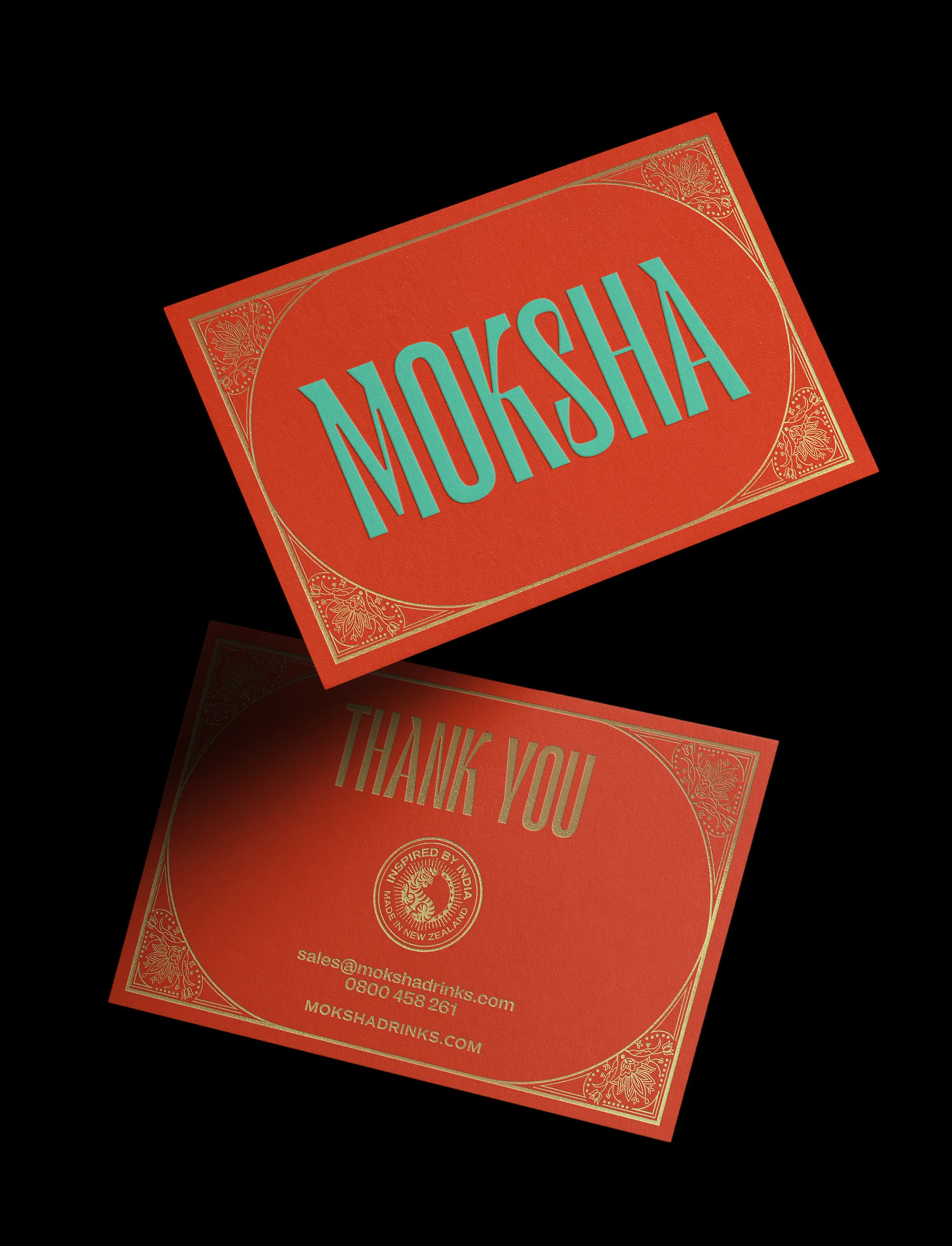 Two red business cards with teal and gold text and details. One card features the brand name "MOKSHA" and the other says "THANK YOU."