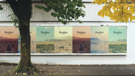 Outdoor billboard display featuring multiple panels for Brother Films under tree branches and autumn foliage.