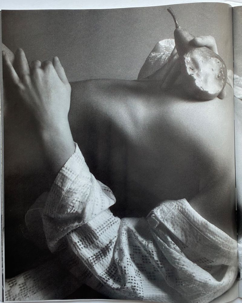 Monochrome upper body shot of a woman with her hands and a halved pear, highlighting body positivity and artistic still life in the studio.
