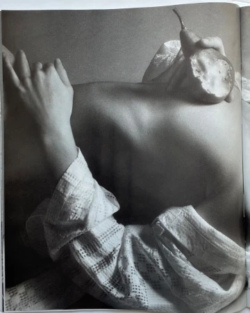 Monochrome upper body shot of a woman with her hands and a halved pear, highlighting body positivity and artistic still life in the studio.