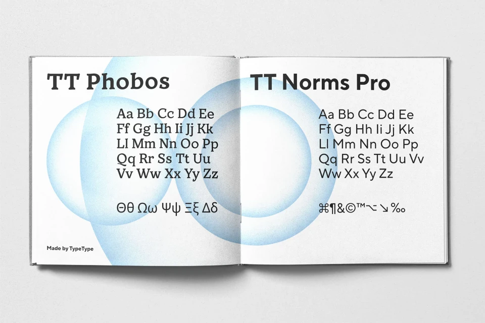 Open book spread featuring typeface samples, displaying the full alphabet of two distinct typefaces, TT Phobos and TT Norms Pro.
